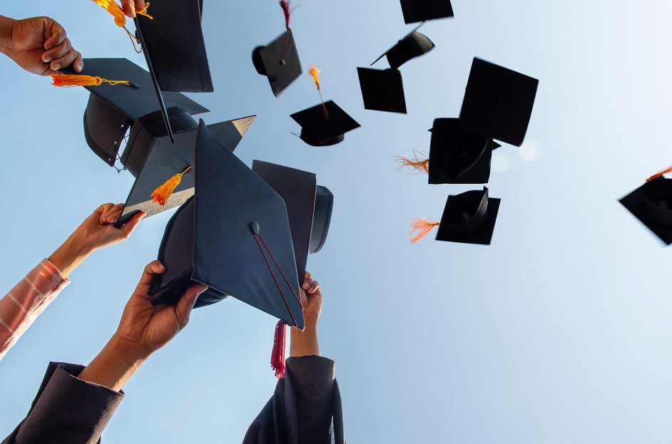 Cropped Hands Of People Throwing Mortarboards Against Clear Sky